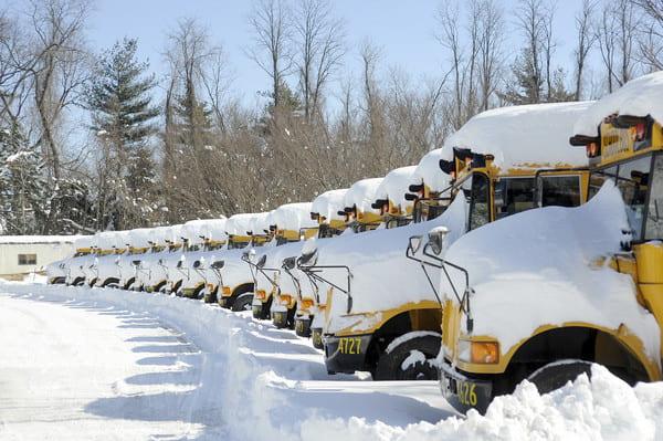 Once upon a time, snow meant a snow day, and the buses would not go anywhere. Now the buses stay covered, but students jump online to attend school virtually. (Photo by Catherine Galioto via Flickr)