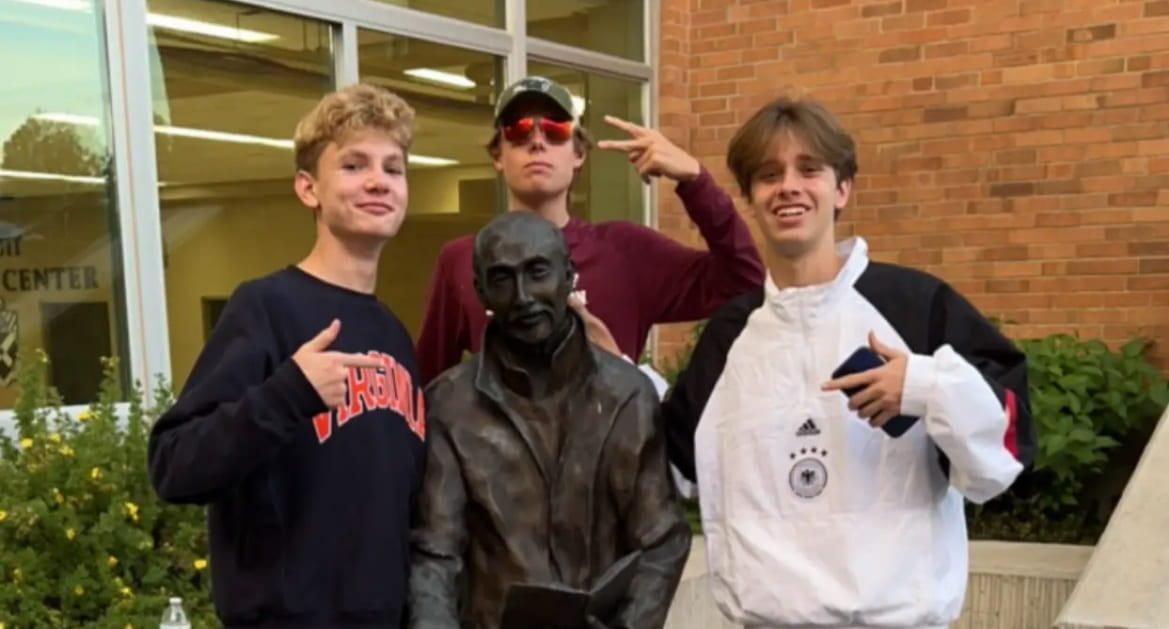 Finn Kramer ‘25, Peter Allen 25’, and Cash Barentzen ‘24 in front of a St. Ignatius statue at McQuaid High School in Rochester.